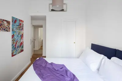 a white room with a bed and a painting at Via Vespasiano Private Apartment in Rome