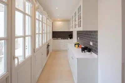 a white kitchen with white cabinets and windows at Via Vespasiano Private Apartment in Rome