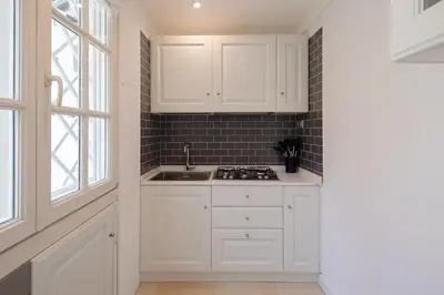 a kitchen with white cabinets and a sink at Via Vespasiano Private Apartment in Rome