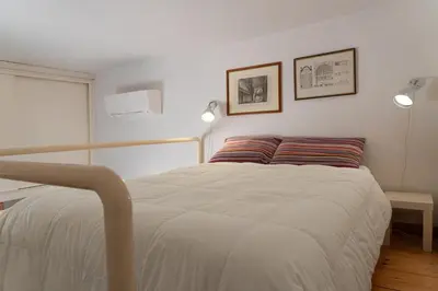a white bed in a room with two lamps at Gallery Apartment, Near The Vatican in Rome