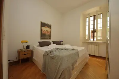 a white bedroom with a bed and a window at Giant Borghese Apartment in Rome