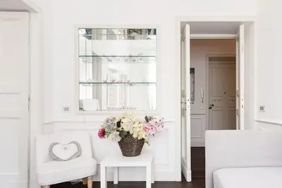 a white living room with a vase of flowers on a table at Re-Imagined Apartment in Historical Building in Rome