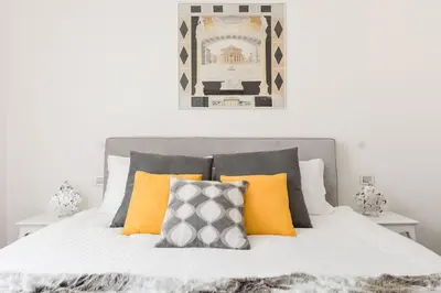 a bedroom with a bed with yellow and grey pillows at Re-Imagined Apartment in Historical Building in Rome