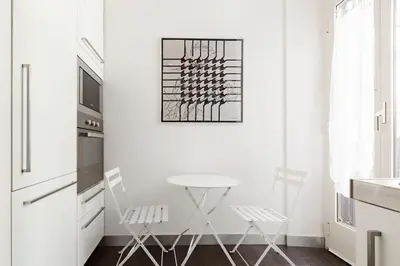 a kitchen with white walls and a white table and chairs at Re-Imagined Apartment in Historical Building in Rome
