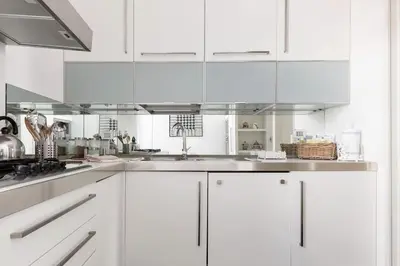 a white kitchen with white cabinets and a sink at Re-Imagined Apartment in Historical Building in Rome