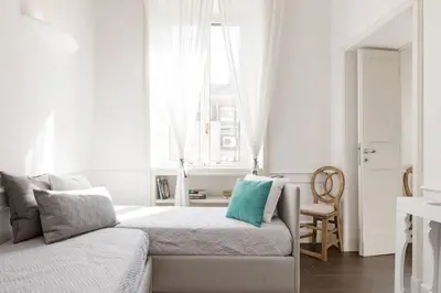 a white living room with a couch and a window at Re-Imagined Apartment in Historical Building in Rome
