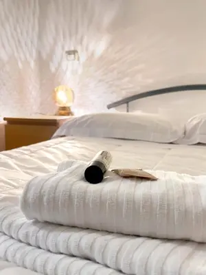 a bottle of wine sitting on a white bed at Spacious Apartment near St Peter's Church in Rome