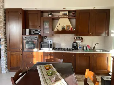 a kitchen with wooden cabinets and a table in it at Roma Battistini 66 Apartment, near Vatican City in Rome