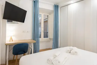 a bedroom with a bed with a blue chair and a desk at Residenza Lungotevere dei Mellini in Rome
