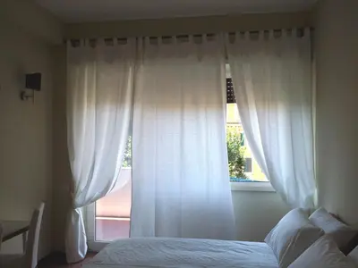 a bedroom with a bed and a window with white curtains at Trastevere Chic in Rome