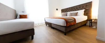 a bedroom with two beds and a wooden floor at Michelangelo Vatican Rooms in Rome