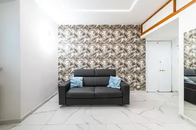 a living room with a black couch in front of a wall at Casa Cate in Rome