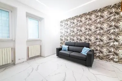 a living room with a black couch and a wall at Casa Cate in Rome