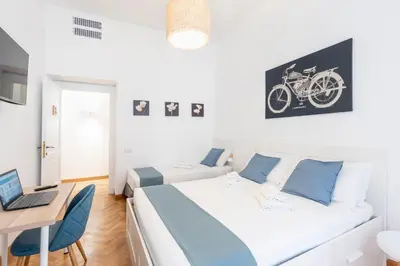a bedroom with two beds and a desk with a laptop at Hostly - Michelangelo Suite Midtown-Center of Rome in Rome