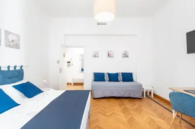 two beds in a white room with blue pillows at Hostly - Michelangelo Suite Midtown-Center of Rome in Rome