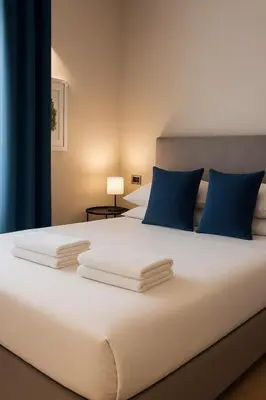 a bedroom with a large white bed with blue pillows at èROMA - COLOSSEO Apartment in Rome