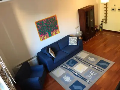 a living room with a blue couch and a rug at Villa Borghese Domus in Rome
