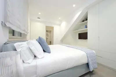a white bedroom with a white bed with blue pillows at YCH-Casa Indipendente in zona Prati in Rome