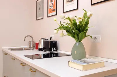a vase with flowers and a book on a kitchen counter at Monti Studio in Rome