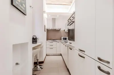 a white kitchen with white cabinets and a skylight at Trastevere House 24 in Rome