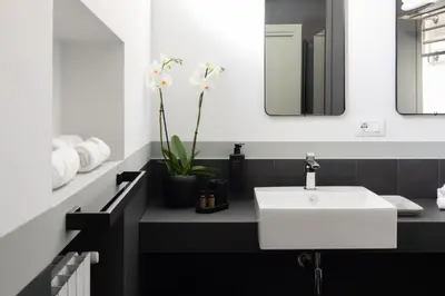 a black and white bathroom with a white sink at Trastevere Charming Rosa Apartment in Rome