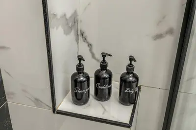 three black bottles sitting on a shelf in a bathroom at Kira Luxury Apartment with terrace in Rome