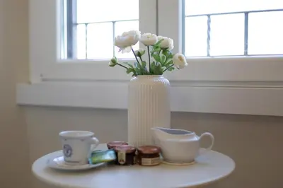 a white vase with flowers and two cups on a table at A due passi dal Colosseo in Rome
