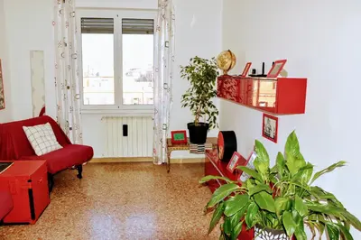 a living room with a red couch and a plant at Aura Home Grazioso Appartamento a Pochi Passi dalla Metro A e C in Rome