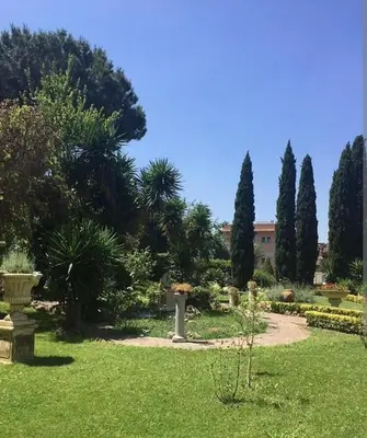 a garden with trees and grass and a building at Aurelia Boutique Apartment in Rome