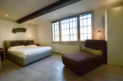 a bedroom with a bed and a chair and windows at Poetico Monolocale Indipendente nell’Antico Pastificio in Rome