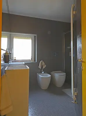 a bathroom with two sinks and a toilet and a window at Angela attico a pochi minuti dal Gemelli e Stazione FL3 direzione San Pietro - Roma centro in Rome
