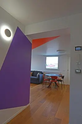 a living room with a purple wall and a table at Angela attico a pochi minuti dal Gemelli e Stazione FL3 direzione San Pietro - Roma centro in Rome