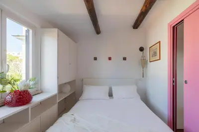 a white bedroom with a bed and a window at iFlat Orient in Rome in Rome