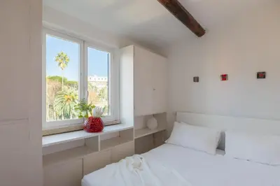 a white bedroom with two beds and a window at iFlat Orient in Rome in Rome