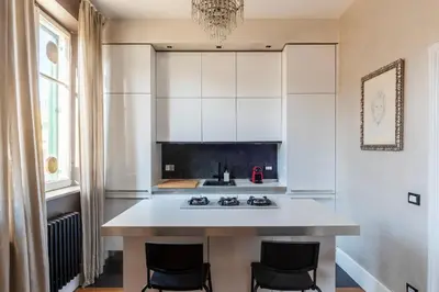 a kitchen with white cabinets and a kitchen island with chairs at GuestHost - Roma Termini Lovely Apartment in Rome