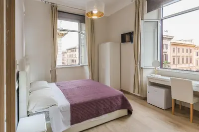 a bedroom with a bed and a desk and a window at Mirabilia House in Rome