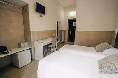a hotel room with two beds and a desk at Mirabilia House in Rome