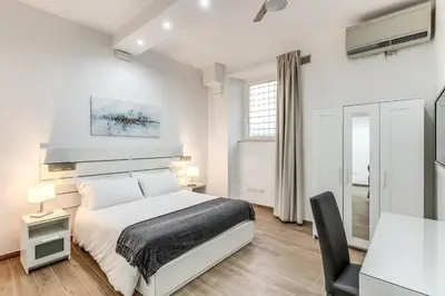 a white bedroom with a bed and a desk at New flat in front StPeter Square in Rome