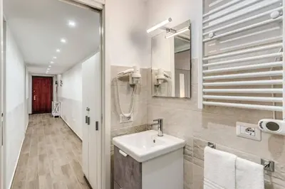 a white bathroom with a sink and a mirror at New flat in front StPeter Square in Rome