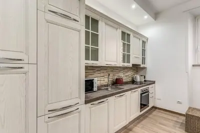 a white kitchen with white cabinets and a sink at New flat in front StPeter Square in Rome
