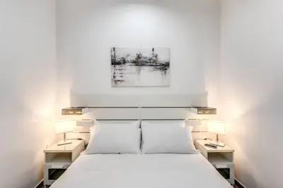 a bedroom with a white bed with two lamps at New flat in front StPeter Square in Rome
