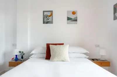 a white bed with three pictures on the wall at Casa Vespi by Hili in Rome