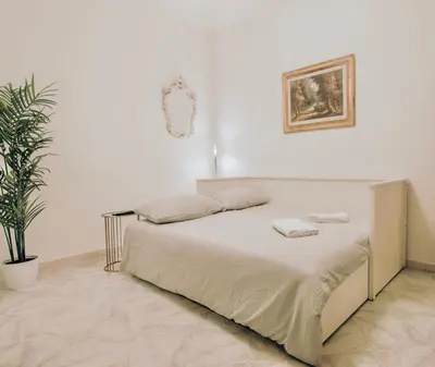 a white bedroom with a bed and a potted plant at Golden Luxury Home - San Giovanni - 3 min to Colosseum in Rome