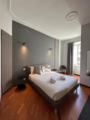 a bedroom with a bed with white sheets and wooden floors at Sopi Vatican Suite Apartment in Rome
