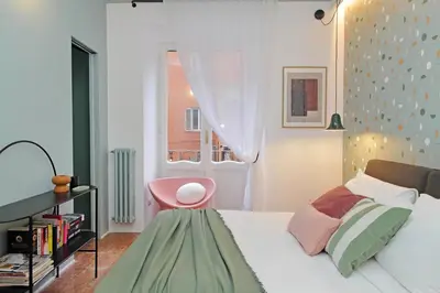 a bedroom with a bed with a pink chair and a window at YCH-Lussuoso appartamento al Colosseo in Rome