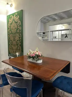 a dining room with a wooden table and blue chairs at Trithome Suite Boutique Barberini in Rome