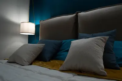 a bed with blue and white pillows and a lamp at Trithome Suite Boutique Barberini in Rome