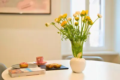 a vase with yellow flowers on a table with donuts at The Best Nest - Home Suite Home NEW OPENING in Rome