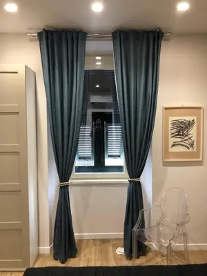 a room with a window with blue curtains and a glass table at Pinciano 1stfloor in Rome