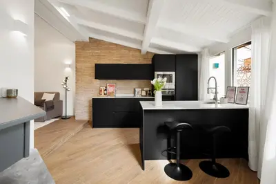 a kitchen with black cabinets and a kitchen island with stools at Terrace Boutique Apartment - Dolce Vita in Rome